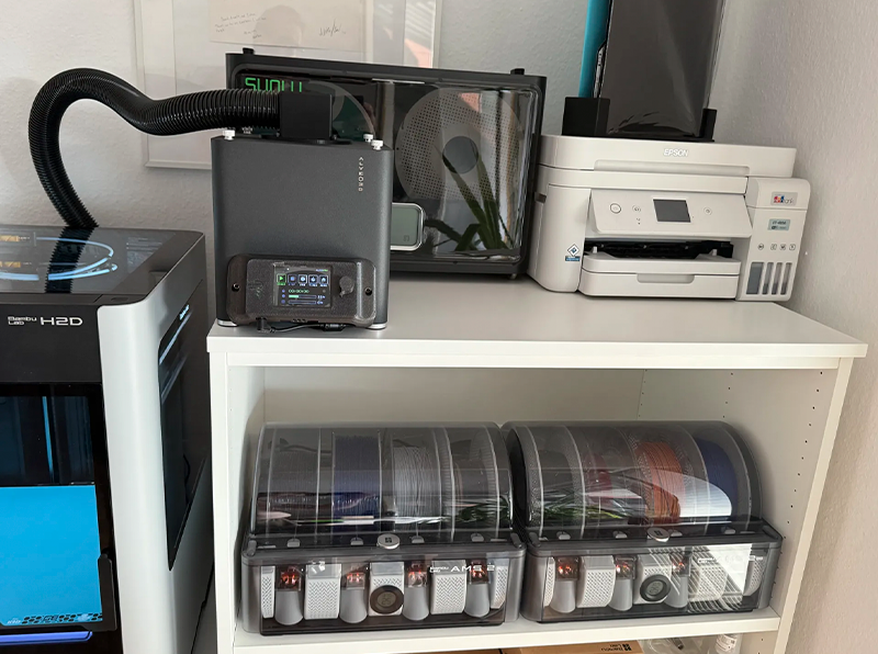 Kompaktes Rauchabsaugsystem aus schwarz eloxiertem Aluminium mit bis zu 3 m ausziehbarem Schlauch, LCD-Display zur Steuerung von Luftstrom und Filtration, Sicherheitswarnungen und USB-Anschluss für Updates.