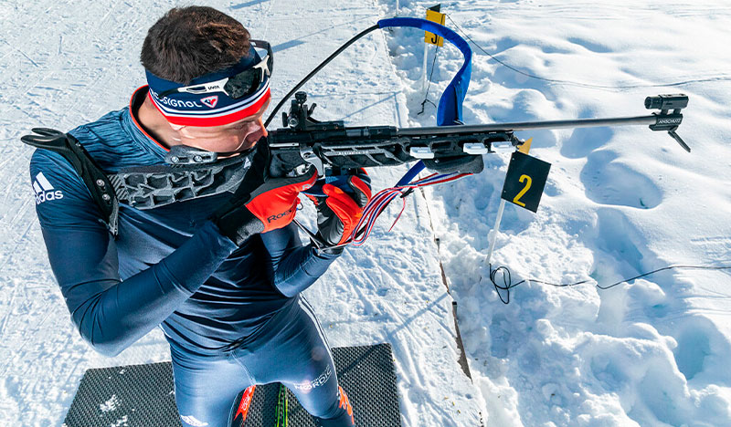 Carabine de biathlon avec des composants imprimés en 3D utilisée en compétition, montrant comment la personnalisation avec l’Ultrafuse® PP GF30 de Forward AM améliore la précision, la stabilité et les performances dans des conditions extrêmes de froid et de haute exigence sportive.
